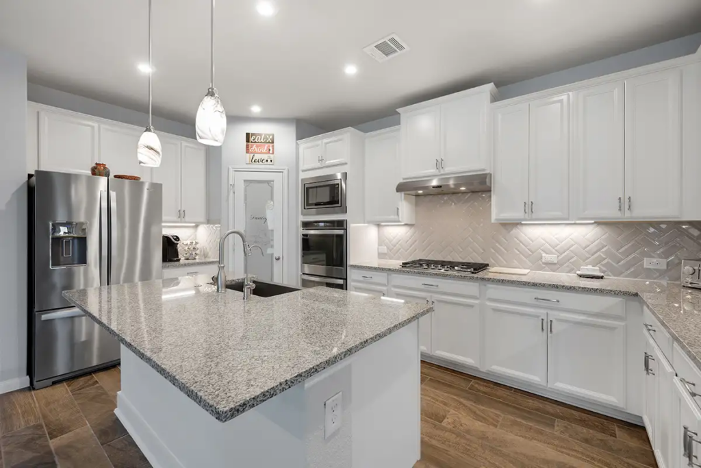 Bright modern kitchen with white cabinets, granite island, and pendant lighting illustrating a completed kitchen renovation design in St. Louis
