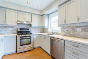 Newly remodeled kitchen with white cabinets, stainless steel appliances, and stone backsplash