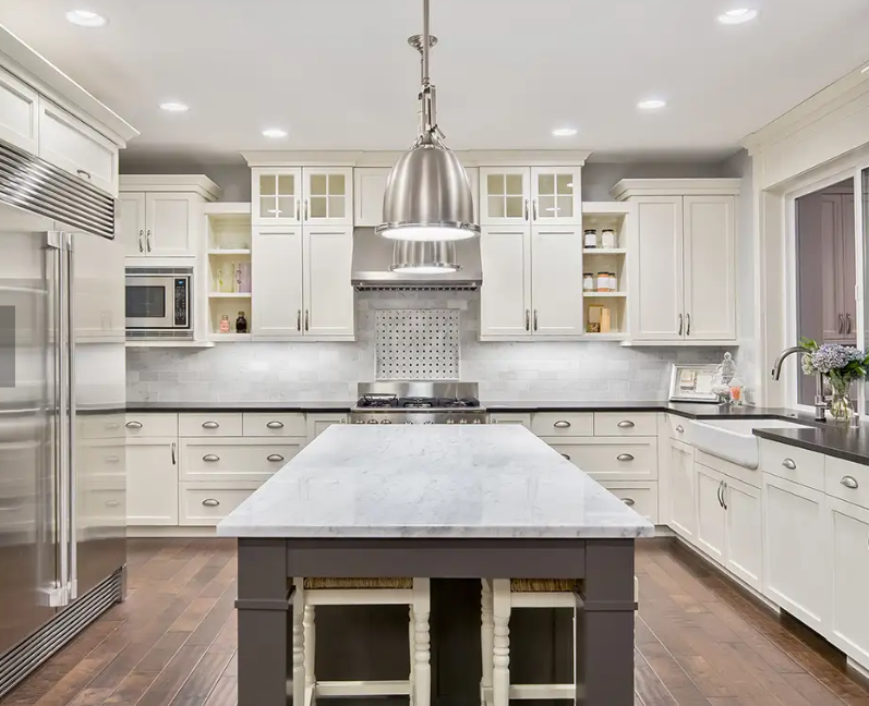 Spacious white kitchen with large island, stainless steel appliances, and modern pendant lighting