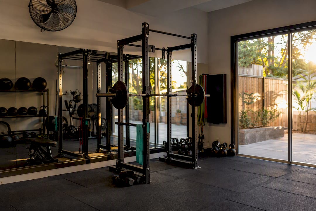 Home gym in a garage with squat rack and glass slider door