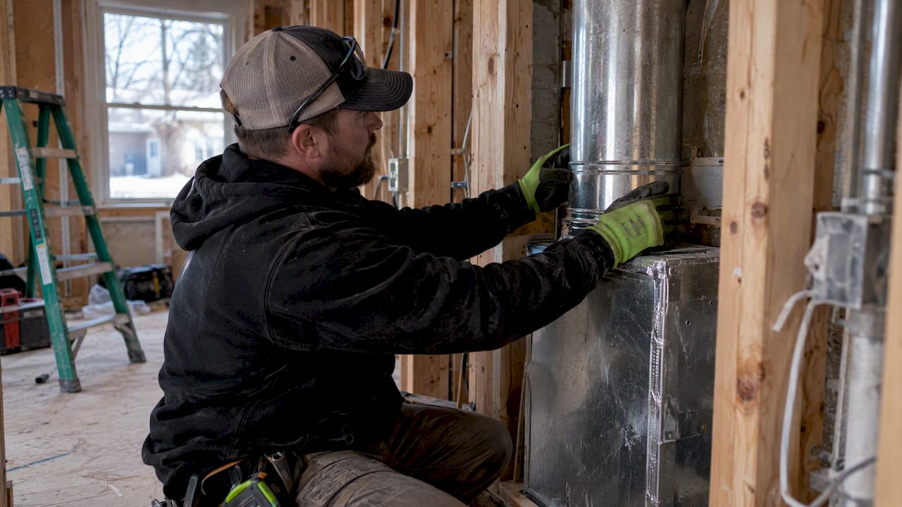 Technician inspecting ducts in an open wall