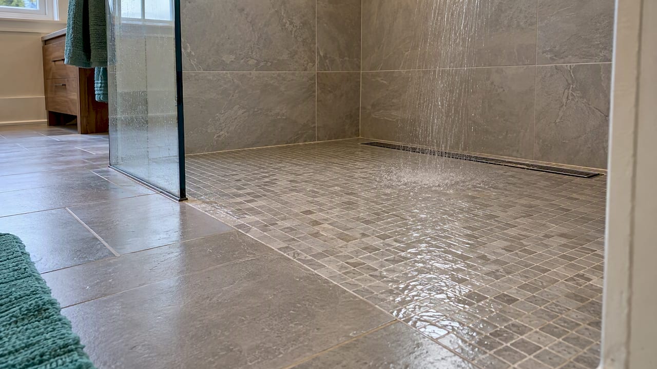 Mosaic shower floor slopes toward linear drain