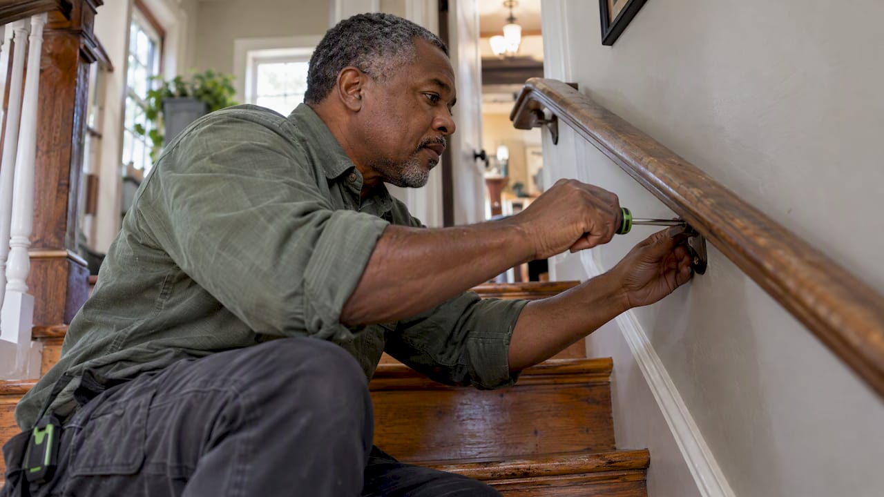 Handyman tightening a loose stair railing
